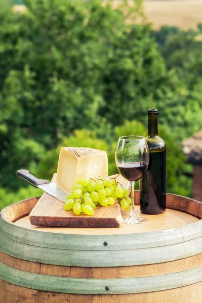 Κόκκινο κρασί, τυρί και σταφύλια με φόντο το tuscan διαμορφωμένο — Φωτογραφία Αρχείου