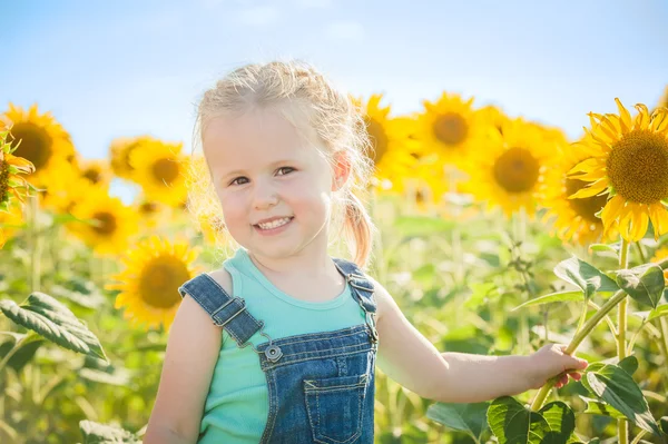 Hermosa chica juega con los girasoles en un día de verano — Foto de Stock