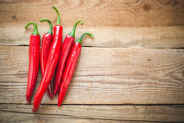 Peperoni succosi e piccanti su un tavolo rustico di legno — Foto Stock