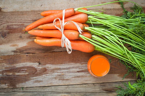 Zanahorias frescas y jugo en una mesa rústica de madera Vintage — Foto de Stock