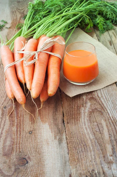 Zanahorias frescas y jugo en una mesa rústica de madera Vintage — Foto de Stock