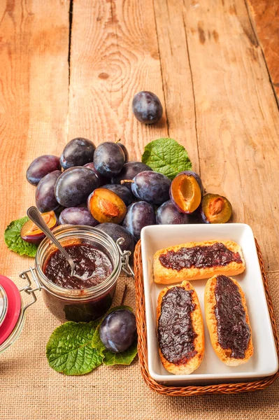 Marmellata di prugne su pane tostato con prugne sullo sfondo — Foto Stock