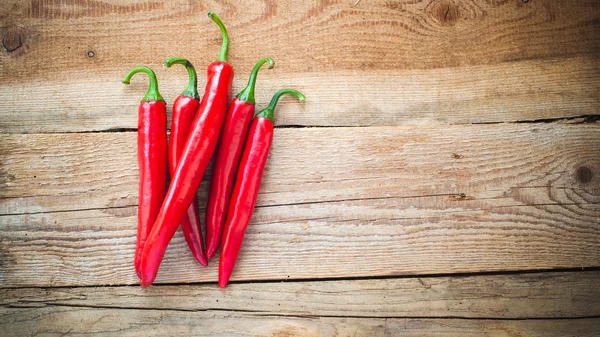 Peperoni succosi e piccanti su un tavolo rustico di legno — Foto Stock