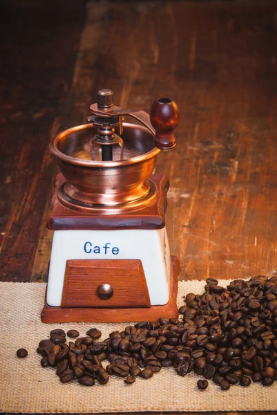 Kaffekvarn med kaffe korn på ett rustikt träbord — Stockfoto