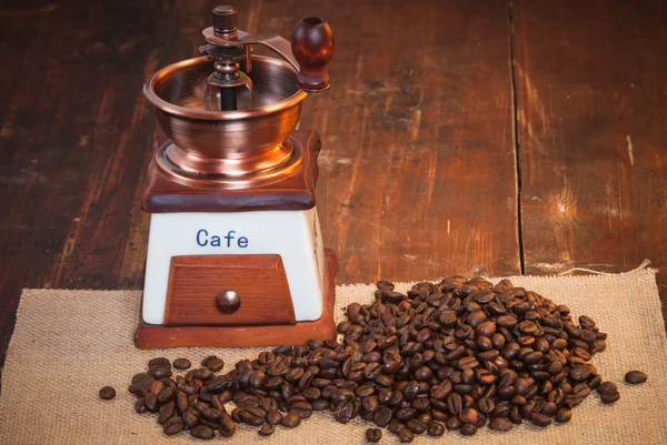 Coffee grinder with coffee grains on a wooden rustic table — Stock Photo, Image