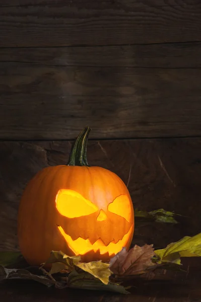 Halloween Pumpkin with glowing eyes and teeth on the leaves with — Stock Photo, Image