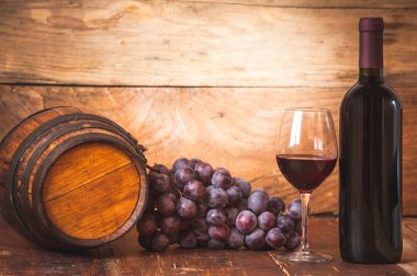 Kırmızı üzüm ve bir şişe şarap ve varil üzerinde ahşap rustik tabl