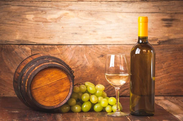 Bicchiere di vino bianco con bottiglia e botte su una rustica ta di legno — Foto Stock