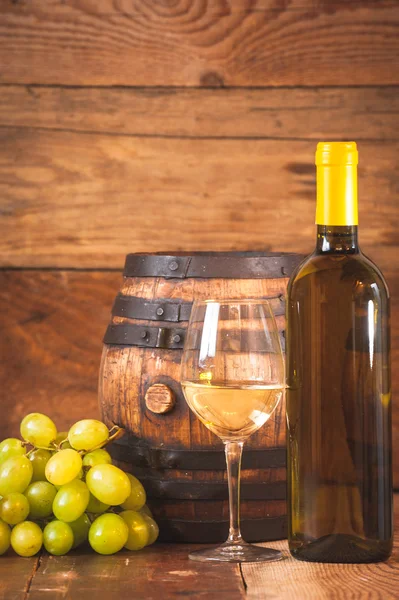 Glas Weißwein mit Flasche und Fass auf rustikalem Holzboden — Stockfoto