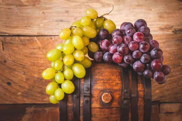 Uvas rojas y blancas en un barril de madera rural — Foto de Stock