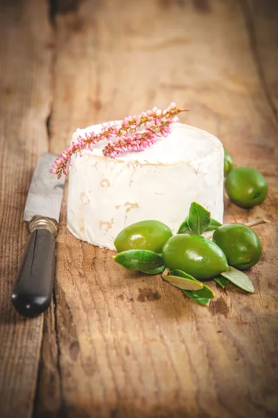 Stinkender Blauschimmelkäse auf einem rustikalen Holztisch mit grünen Oliven — Stockfoto