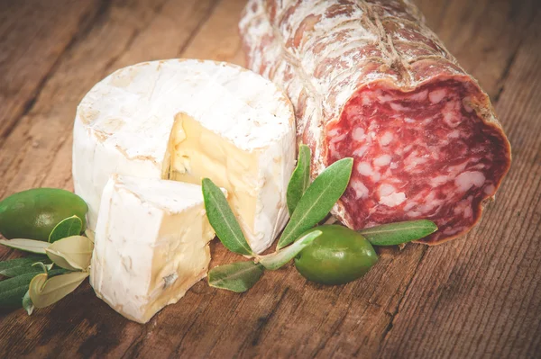 Smelly blue cheese on a wooden rustic table with salami and oliv — Stock Photo, Image