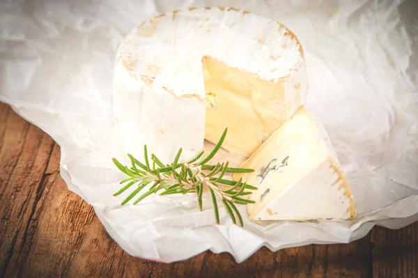 Lugtende blå ost på hvidt papir et træ rustikt bord - Stock-foto