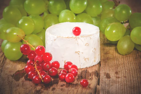 Smelly blue cheese on a wooden rustic table with red currants — Stock Photo, Image