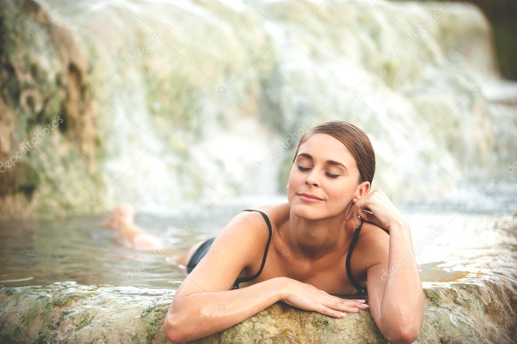 Pretty young woman takes a bath in the natural thermal waters of
