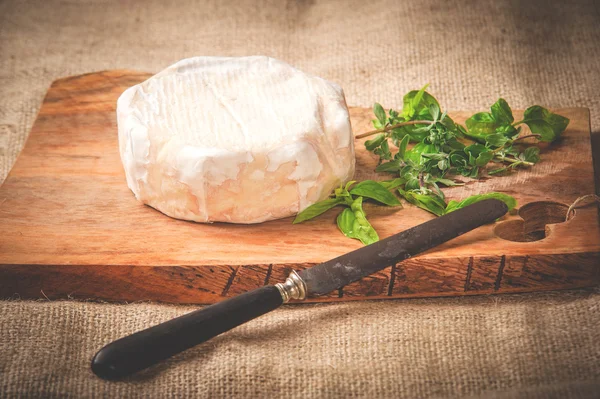 Formaggio blu puzzolente su un tavolo rustico in legno con coltello e basilico — Foto Stock