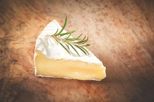 Bit illaluktande camembert ost på ett rustikt träbord — Stockfoto