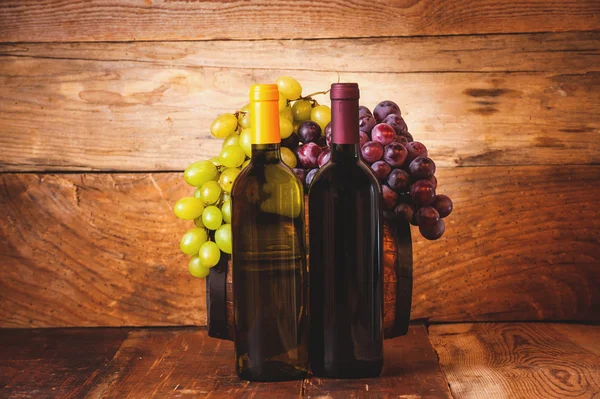 Botella de vino tinto y blanco con uvas y barril en madera rusti — Foto de Stock