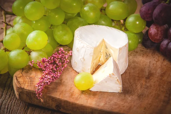 Stinkender Blauschimmelkäse auf einem rustikalen Holztisch mit Trauben — Stockfoto