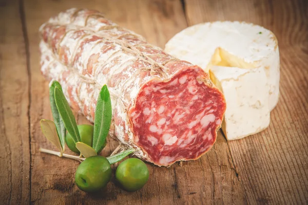 Smelly blue cheese on a wooden rustic table with salami and oliv — Stock Photo, Image