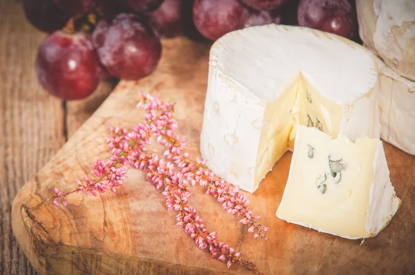 Queijo azul fedorento em uma mesa rústica de madeira com uva — Fotografia de Stock