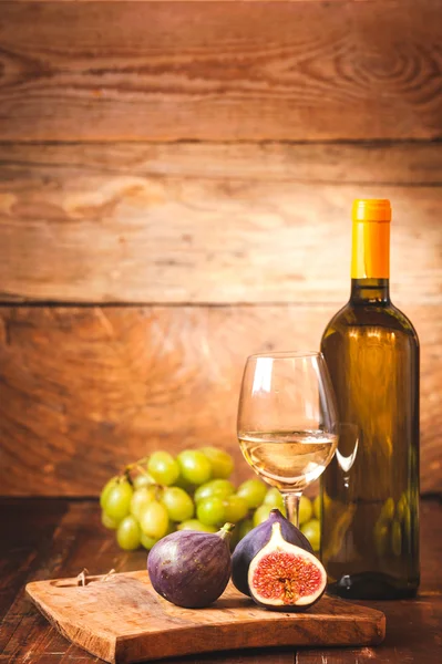 Canna di vino bianco con bottiglia, bicchiere e fichi su una scheda rustica — Foto Stock