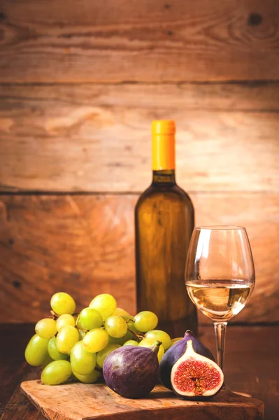 Canna di vino bianco con bottiglia, bicchiere e fichi su una scheda rustica — Foto Stock