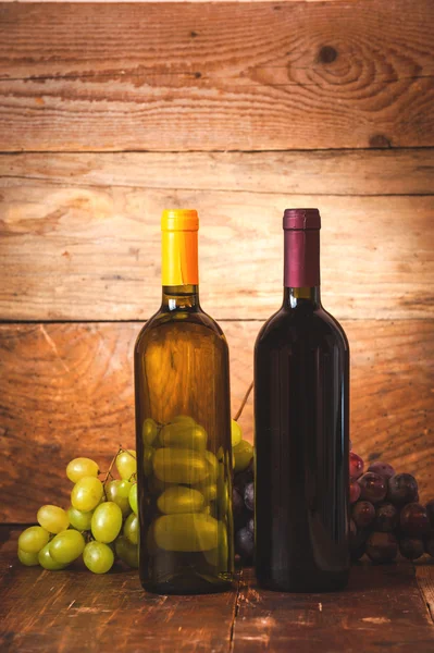 Bouteille de vin rouge et blanc avec raisins et tonneau sur rusti en bois — Photo
