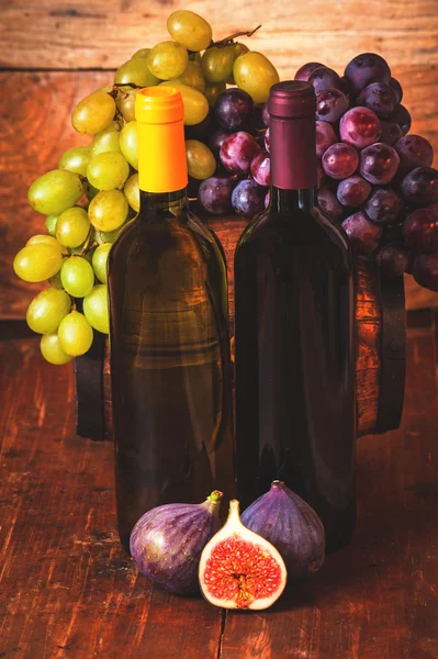 Garrafa de vinho vermelho e branco com uvas e barril em rusti de madeira — Fotografia de Stock