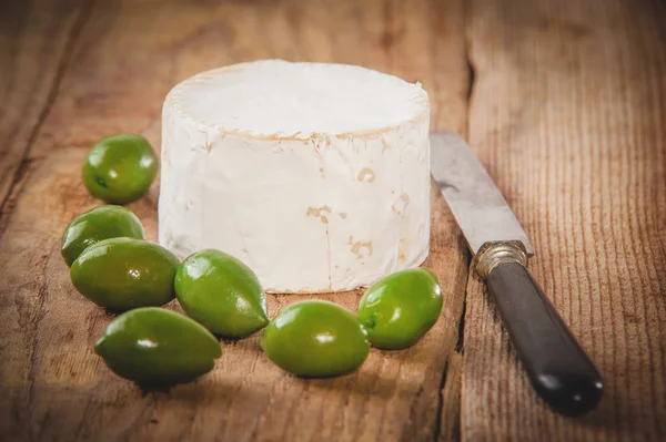 Queso azul maloliente sobre una mesa rústica de madera con aceitunas verdes —  Fotos de Stock