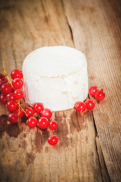 Smelly blue cheese on a wooden rustic table with red currants — Stock Photo, Image
