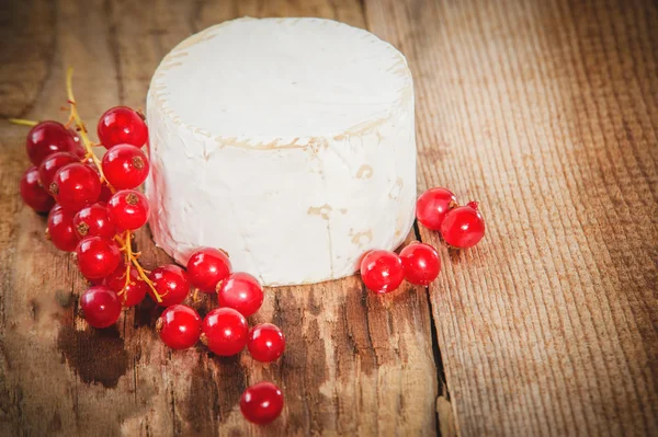 Stinkende blauwe kaas op een rustieke houten tafel met rode aalbessen — Stockfoto