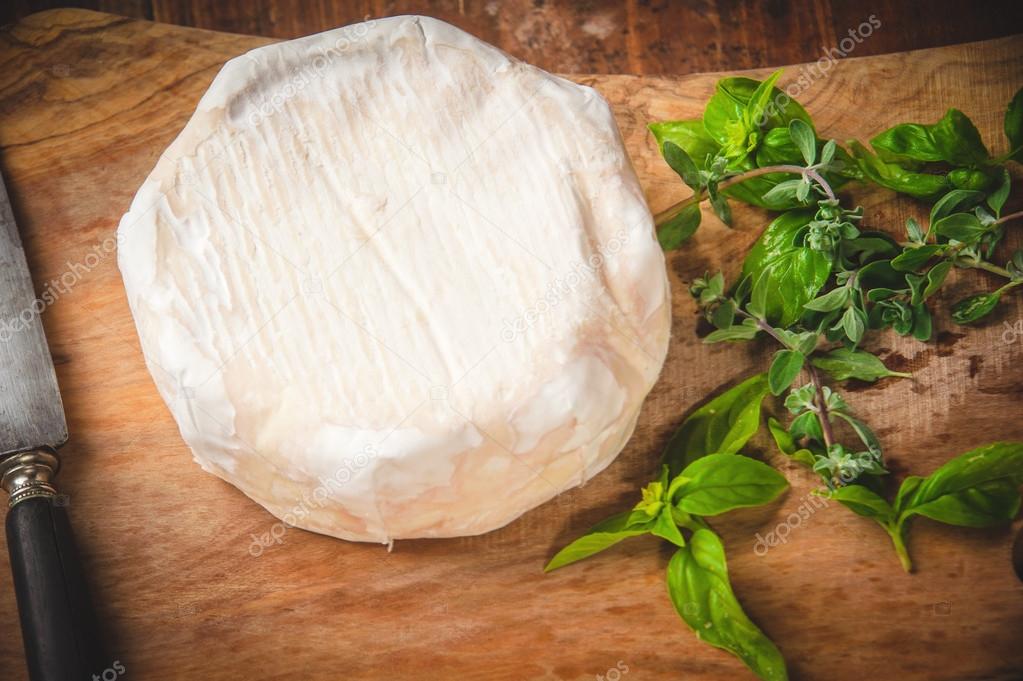 Smelly blue cheese on a wooden rustic table with knife and basil