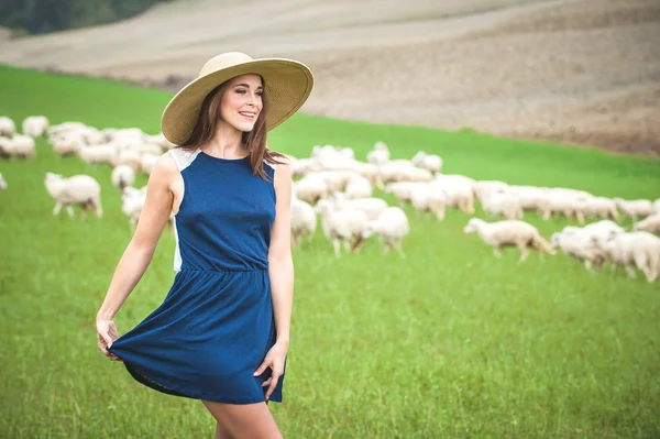 Schöne Frau auf einem Feld zwischen den toskanischen Schafen — Stockfoto