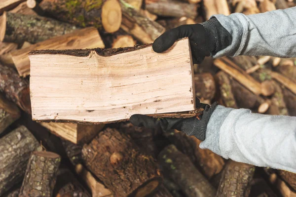 Bois de chauffage dans un morceau de bois stocké sur la pile, les mains tenant un — Photo