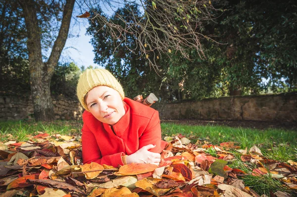 Mujer sonriente de otoño acostada sobre hojas en el parque — Foto de Stock