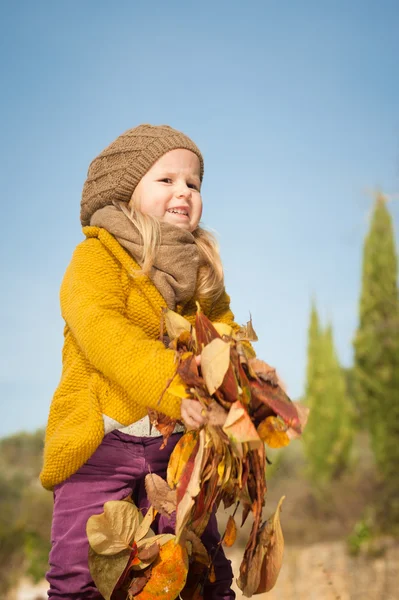 Hermosa chica, rubia sonriente juega con las hojas de otoño — Foto de Stock