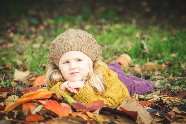 Krásná dívka, s úsměvem blondýnka hraje s podzimní listí — Stock fotografie