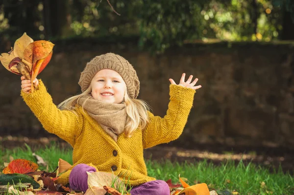 Hermosa chica, rubia sonriente juega con las hojas de otoño — Foto de Stock