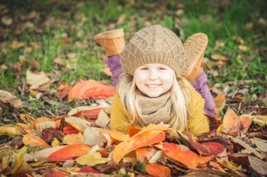 Güzel kız, sarışın gülümseyen sonbahar yaprakları ile çalış