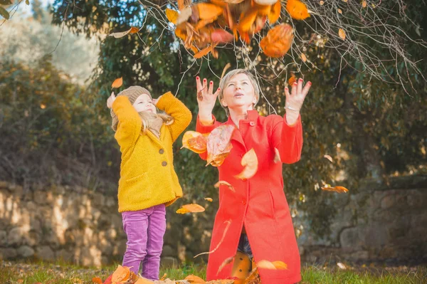 Schönes Mädchen, lächelnde Blondine spielt mit den Herbstblättern — Stockfoto
