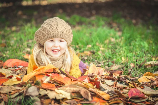 Красивая девушка, улыбающаяся блондинка играет с осенними листьями — стоковое фото
