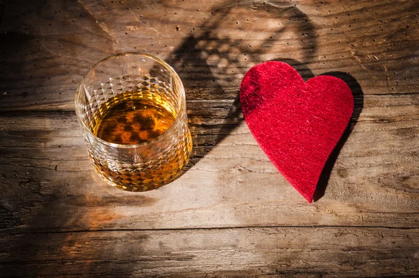 Καρδιά και ένα ποτήρι αλκοόλ σε ένα ξύλινο τραπέζι στο μπαρ — Φωτογραφία Αρχείου