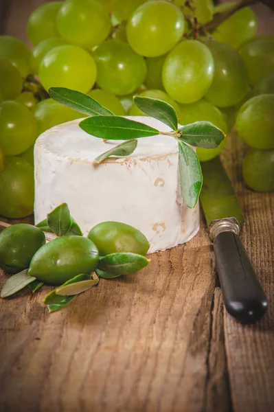 Stinkender Blauschimmelkäse auf einem rustikalen Holztisch mit Trauben — Stockfoto