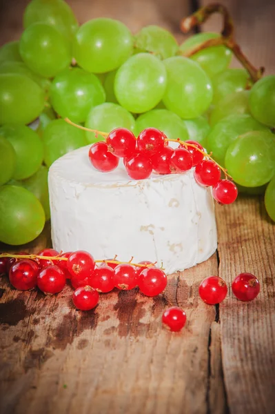 Smelly blue cheese on a wooden rustic table with red currants — Stock Photo, Image