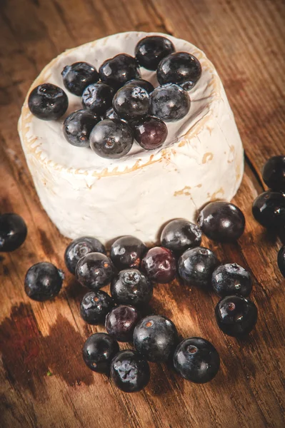 Smelly blue cheese on a wooden rustic table with blueberries — Stock Photo, Image