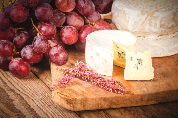 Δύσοσμα μπλε τυρί σε ένα ξύλινο τραπέζι ρουστίκ με σταφύλι — Φωτογραφία Αρχείου