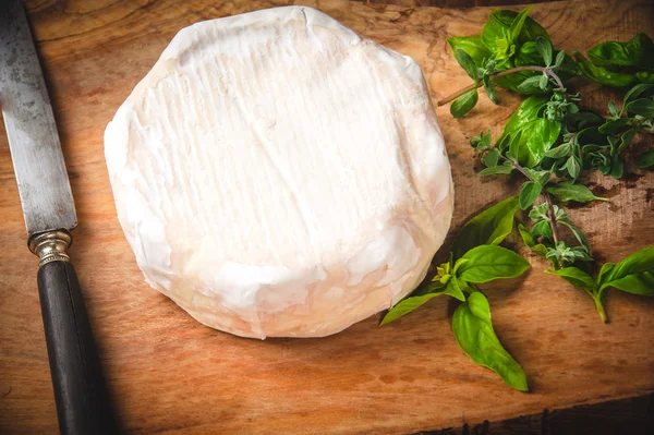 Smelly blue cheese on a wooden rustic table with knife and basil — Stock Photo, Image