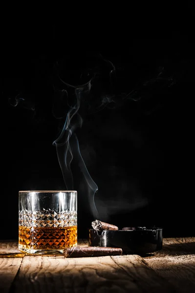 Vaso de alcohol y cigarro sobre fondo negro — Foto de Stock