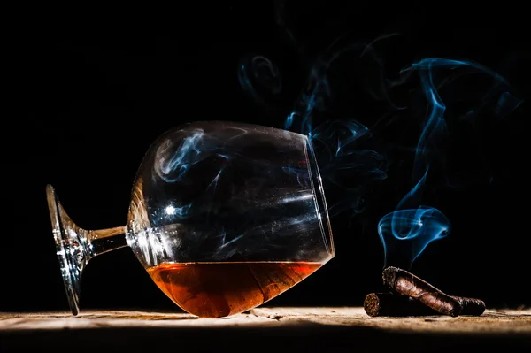 Glas av alkohol och rökning ädla cigarr på svart bakgrund — Stockfoto